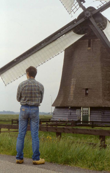 a local stands in clogs in front of a windmill