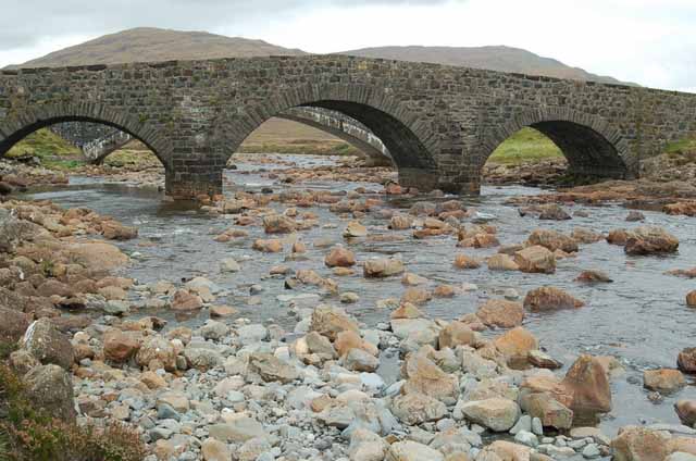a bridge crosses the stream at the foot of the Cuillins