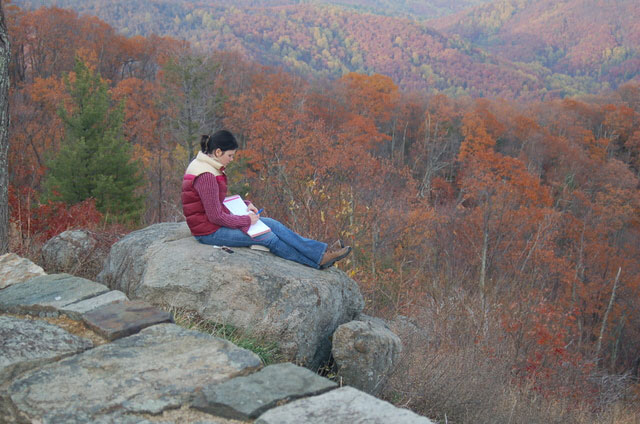 girl sits on rock overlooking hills